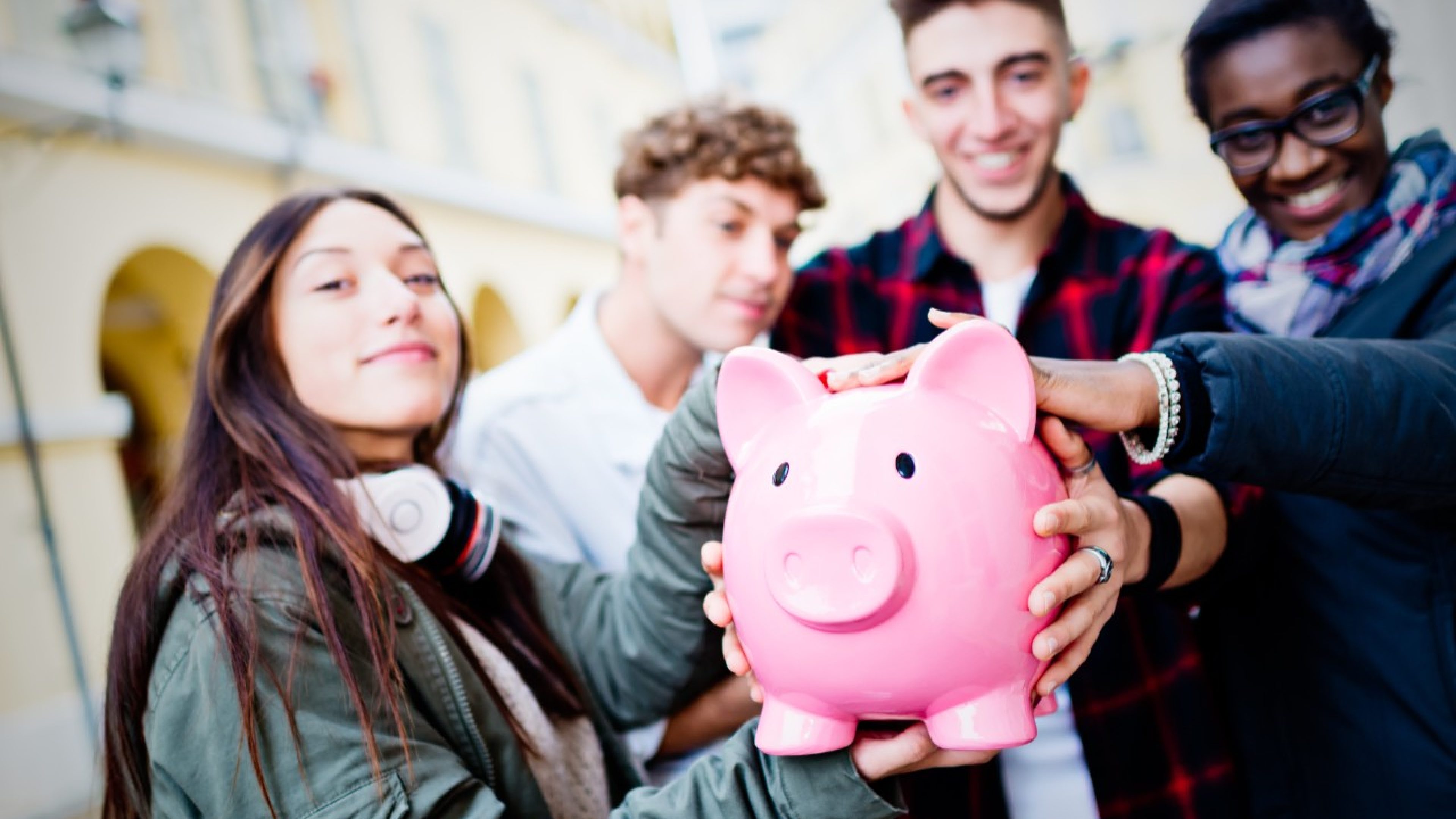 Group of mixed race people holding Piggy Bank