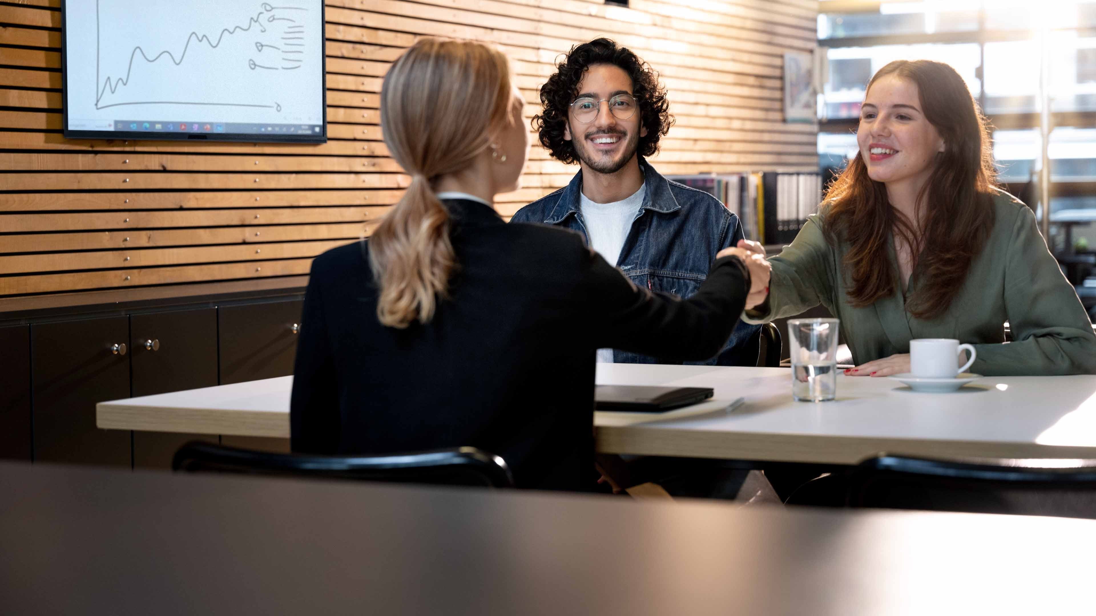 A Swiss Life advisor welcomes a young couple to a customer meeting.