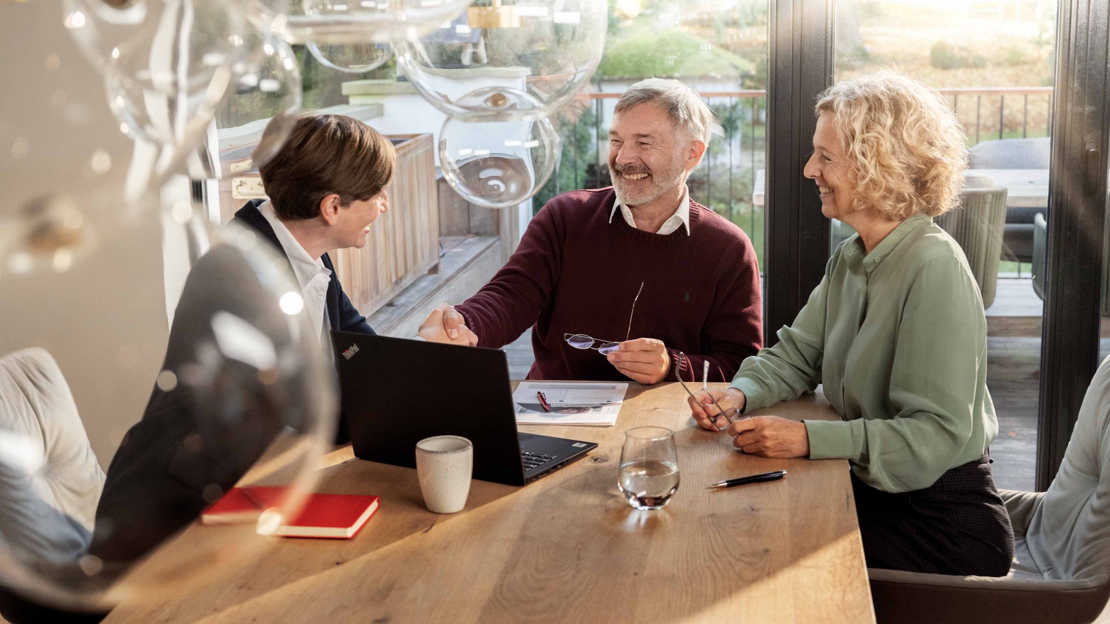 A Swiss Life Select advisor shakes hands with a customer and his partner.