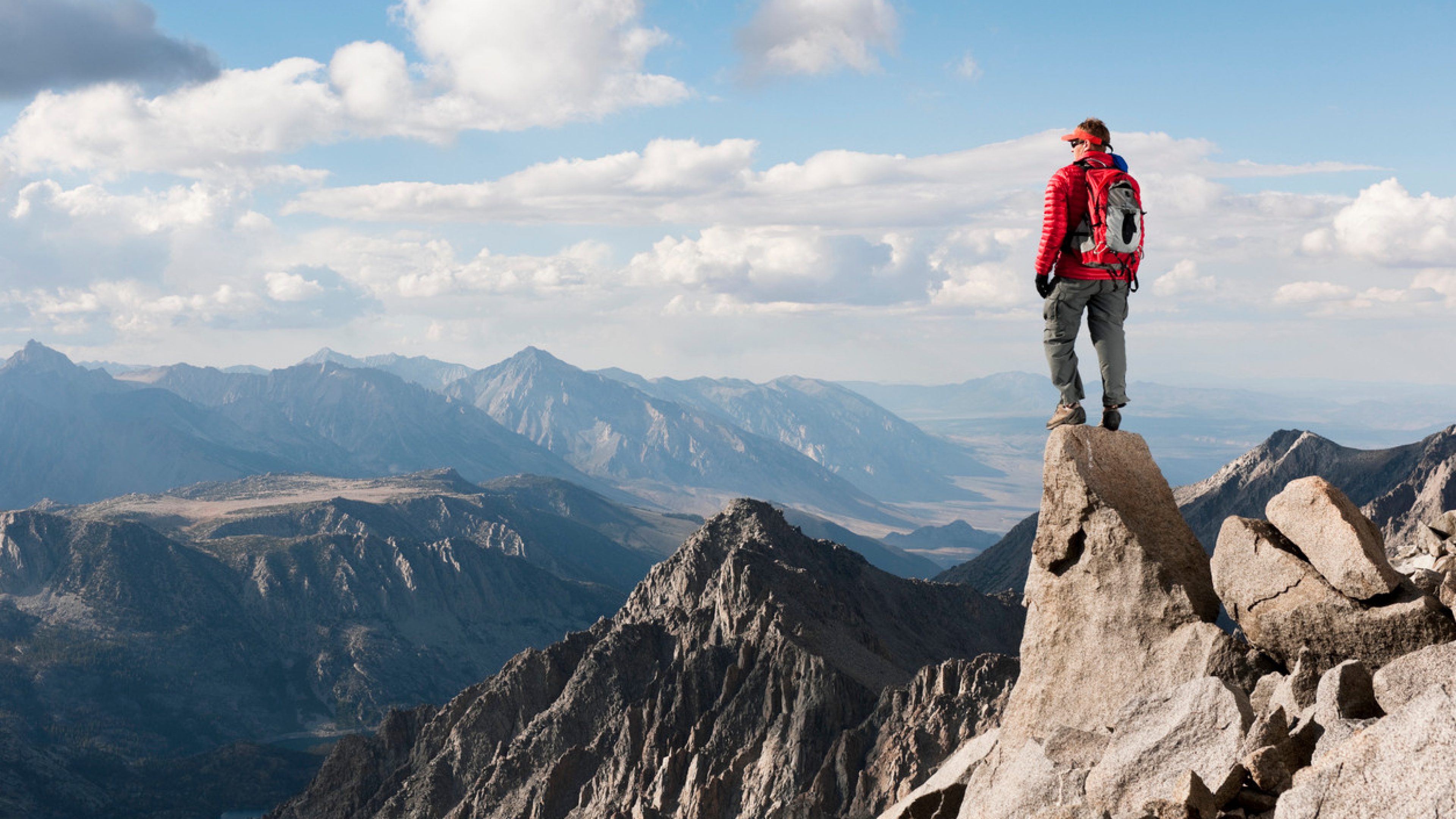 A man on top of a mountain looking at view 