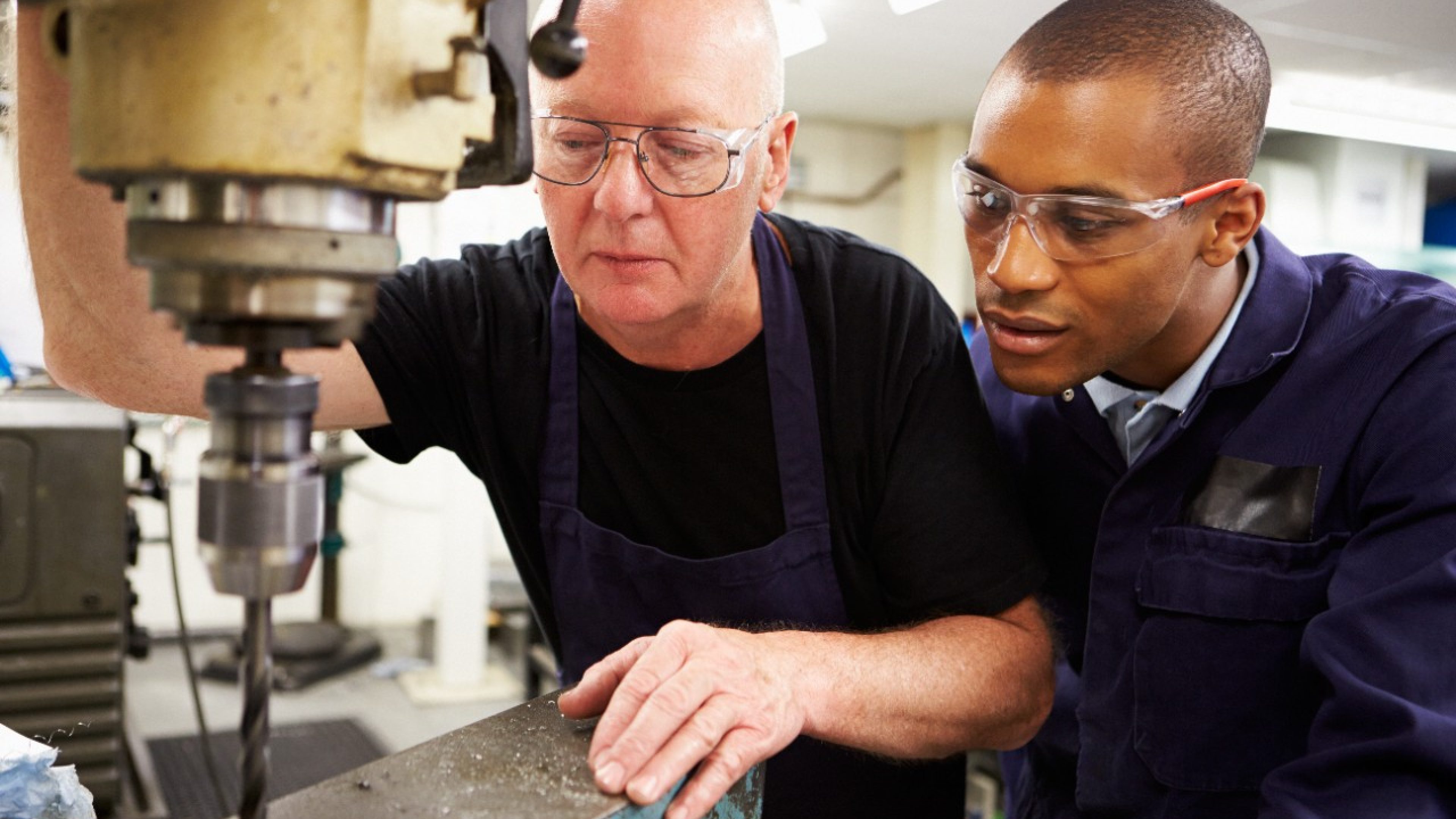 Engineer Teaching Apprentice To Use Milling Machine Together